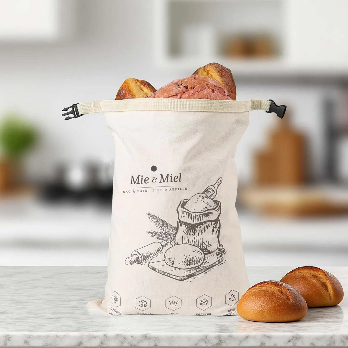 Sac à pain Mie & Miel rempli de pains, fermé par sa boucle clipsable